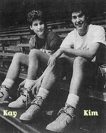 Twin sister girl basketball players, Kay Fredrickson on left, Kim Frederickson on right, sitting in stands. Playing for Jerry Thompson Insurance Agency of Durand, Wisconsin in 1987. From The Capital Times, Madison, Wisconsin, February 12,1987.