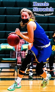 Image of a masked Kenzie Sirowich, in blue uniform, driving with the basketball, for the Seymour Wildcats team in Connecticut.