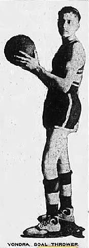 Side view, full body, of Ed (Sport) Vondra, 1921-22 Brainard High School (Nebraska), holding basketball. Titled 'Vondra, Goal Thrower' from The Nebraska Journal, Lincoln, Nebraska, February 12, 1922.