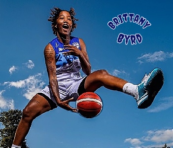 Image of Irish SuperLeague player Brittany Byrd, on the Address UCC Glanmire team, shown high in air with basketball between her legs. 