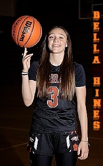 Photo (by Michelle Hines) of New Mexican girls basaketbal player Bella Hinesm number 3, in black uniform with red lettering, of her Eldorado high school team, spinning a basketball on her right finger.