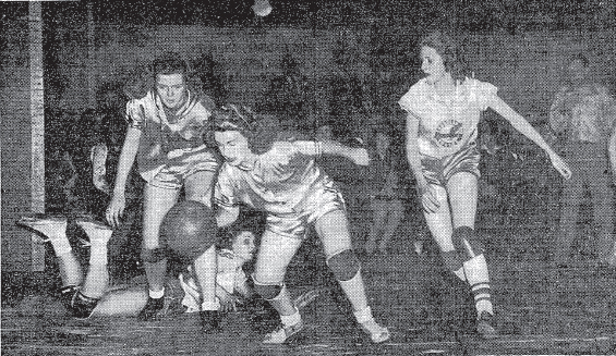 Action shot of Nashville Vultee Aircraft Bomberettes, in a 64 to 30 win over the St. Simon Stock Alpines of the Bronx, in a game played under collegiate men's rules at the Bronx Winter Gardens, January 21, 1945, before 1,000 fans, in a game played under collegiate men's rules. The picture is titled ALPINE CAPTAIN DRIBBLING BALL IN GAME AT BRONX WINTER GARDEN, and is from the New York Times, 1/22/1945. It reads (and pictures): 'Miss Helen Kelly getting away after she intercepted a pass intended for Miss Mary Jane Marshall (on floor) of the Vultees. The others are Miss Gloria Wood (left) of Alpines and Miss Doris Weems of the Tennessee team.' Marshall scored 9 points, and Alline Banks 34 points.