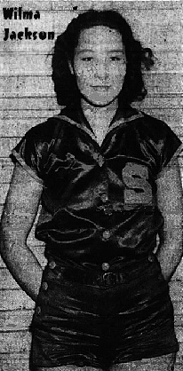 Image of Wilma Jackaon, late 1930s girl basketball player for Sullivan High School, Tennessee, in silk or satin uniform with shorts, an S on the left breast, hands behind her back, against a brick wall, posing. From the Johnson City Sunday Press-CHronicle, Johnson City, Tenn., January 21, 1940.