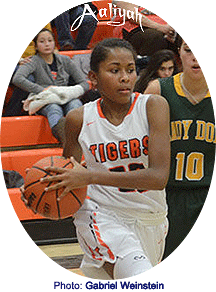 Image of Aaliyah Quintana, Tao High School girls basketball player, driving with ball, in white uniform with orange TIGERS in action shot from 2015-16 season.