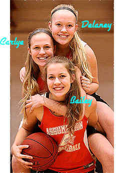 Image of triplets, girls basketball players for Assumption High School, Davenport, Iowa. Posed with Delaney Brown on top, Carlye Brown in the middle and Bailey Brown at bottom, all in orange warm up uniforms.
