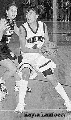 Kayla Lambert, Brockton Warrior (Montana) high schoolbasketball player, number 4, dribbling upcourt, facing left.