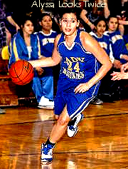 Image from Spring 2014 NAIA Region 7 championship game, of Alyssa Looks Twice of Oglala Lakota College women's basketbaall team, driving upcourt with the ball. In blue uniform, number 24.