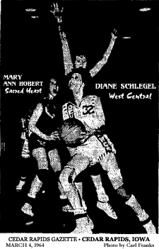 Image of Diane Schlegel, West Central High (Maynard, Iowa) basketball player, in action, in game where she scored 52 points in 1an 86-79 victory over Sacred Heart of Monticello, in a District Playoff consolation game at Manchester. Schlegel is driving on an unidentified Sacred Heart player as well as Mary Ann Hobert, Sacred Heart guard, #51, to left of picture. From Cedar Rapids Gazette, Cedar Rapids, Iowa, March 4, 1964, which misattributed 54 points to Schlegel. She scored 52. Gazette photo by Carl Franks.