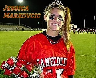 Image of Jessica Markovcic, as the 2011 homecoming queen of Screven County High School (South Carolina), in red GAMECOCKS uniform, wearing tiarra, with flowers. On football field with goal posts in background.